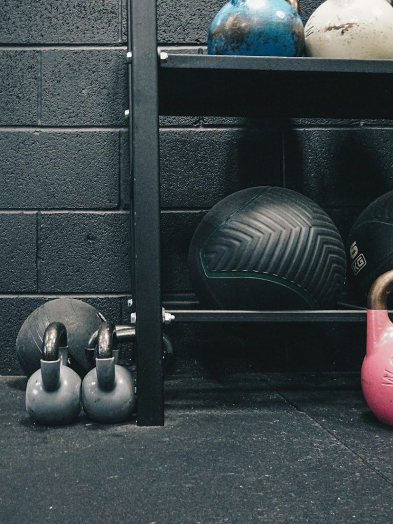 Fitnessgeräte auf einem Regalsystem: Kettlebells, Medizinbälle und Gewichte.