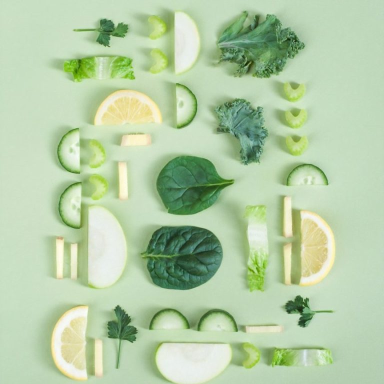 Bunte Anordnung von frischem Obst und Gemüse auf grünem Hintergrund.