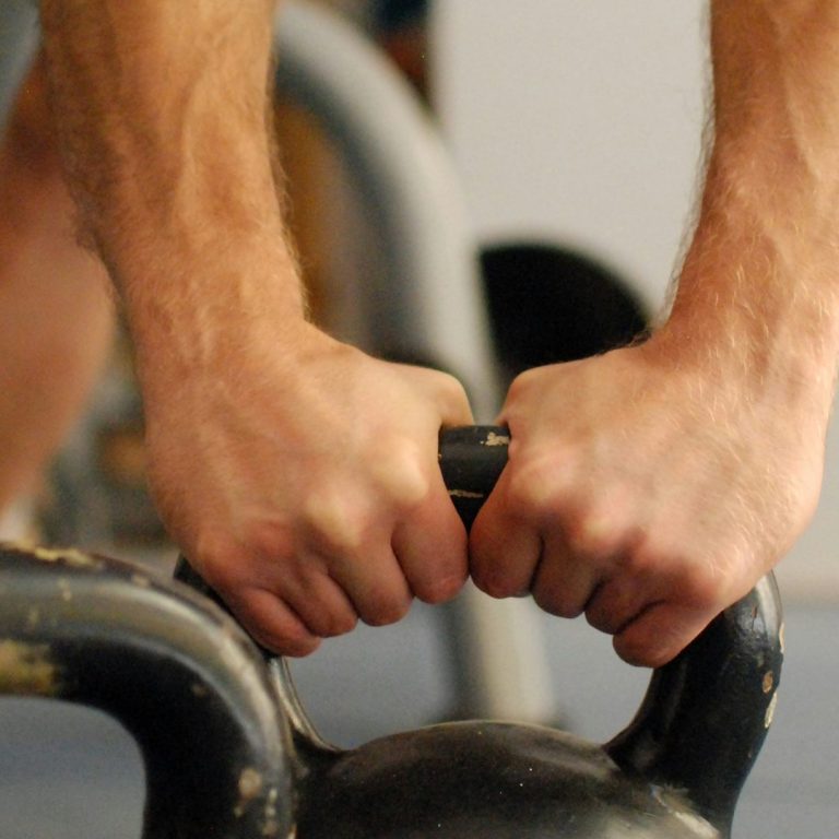 Nahaufnahme von Händen, die eine Kettlebell festhalten während des Trainings.