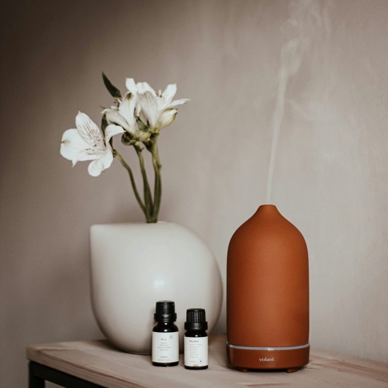 Brauner Diffusor mit Dampf, weißen Blumen und zwei ätherischen Ölen auf einem Tisch.